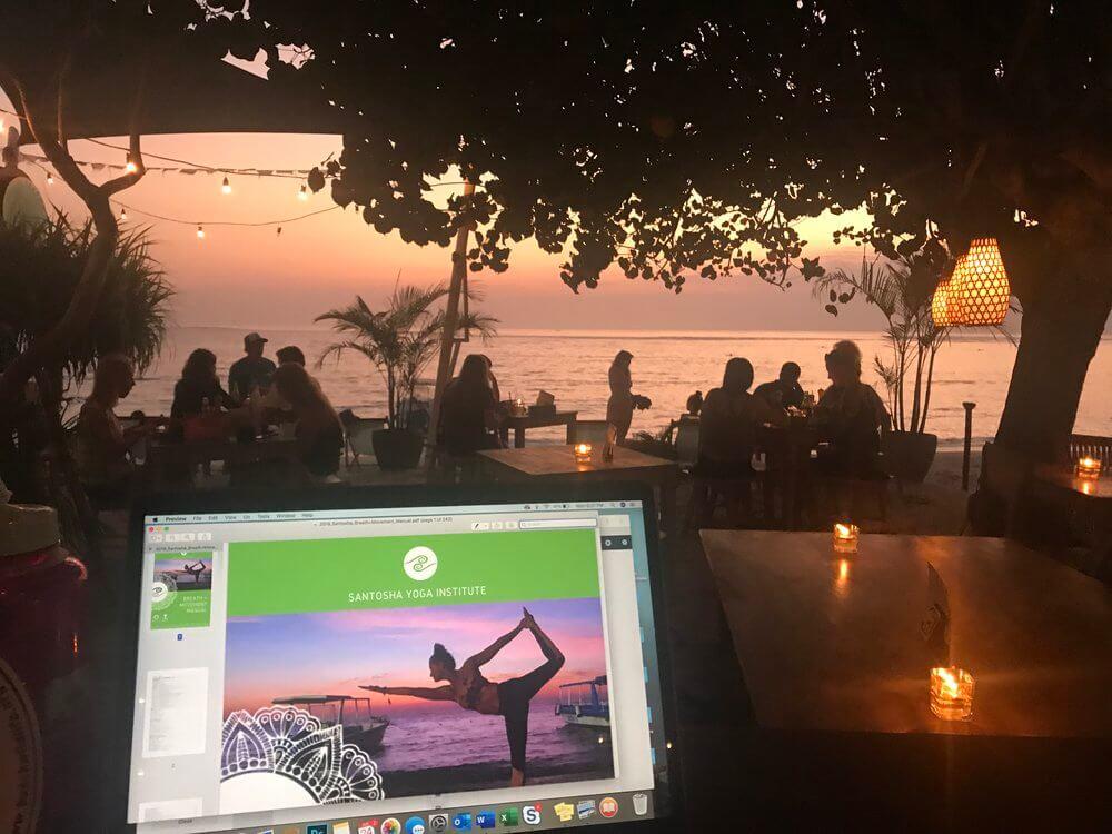 santosha yoga institute manual on computer in front of nusa lembongan sunset