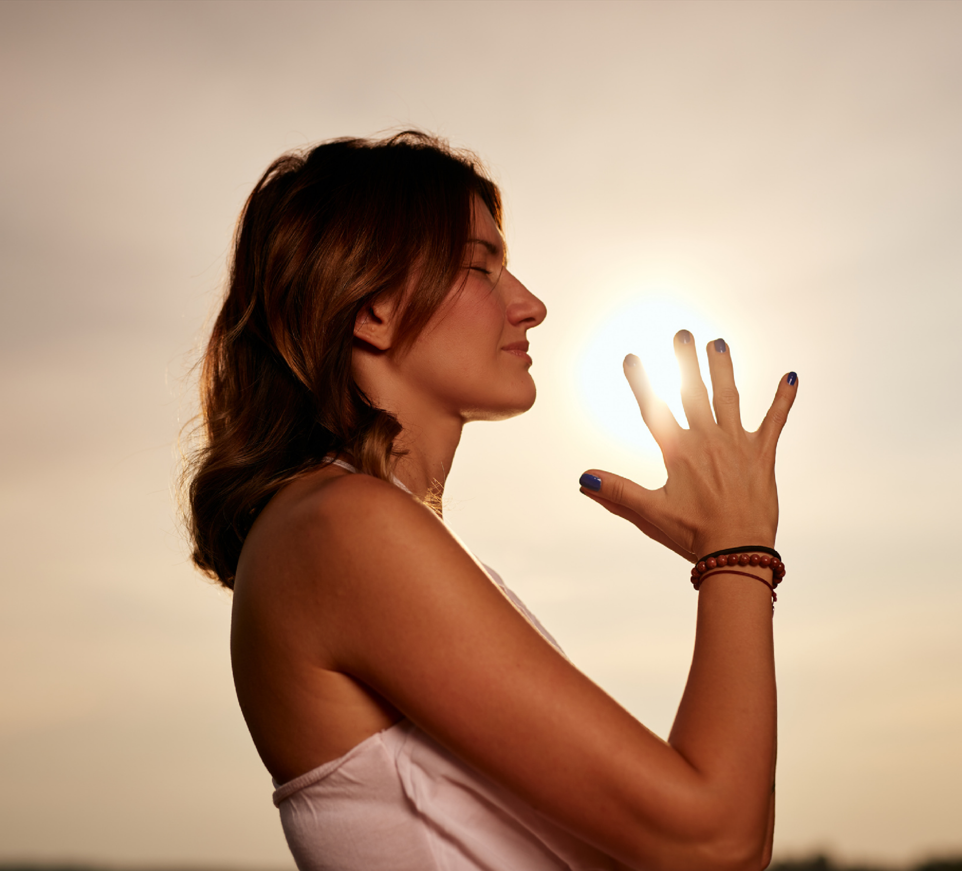 A woman meditating with her eyes closed, bathed in warm sunlight, during a yoga teacher training. The serene moment represents the journey to find your truest calling and most authentic self through yoga practice.