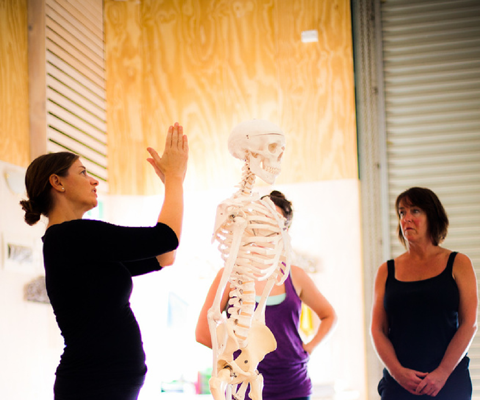 Yoga teacher training participants learning anatomy with a skeleton model from a renowned and highly-passionate instructor. The specialized teaching module helps deepen their understanding of the body in yoga practice.