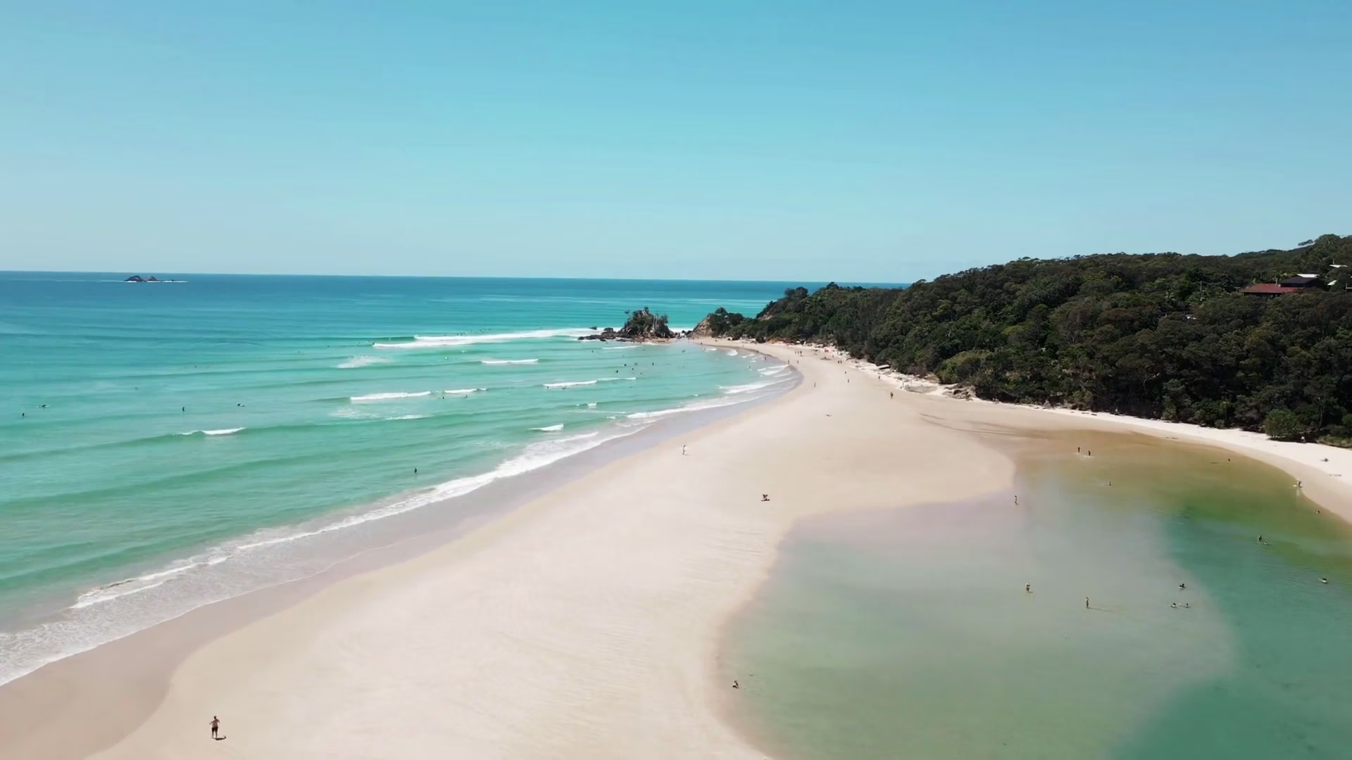 Aerial view of Byron Bay’s white sand beach and turquoise waters with lush greenery on the headland