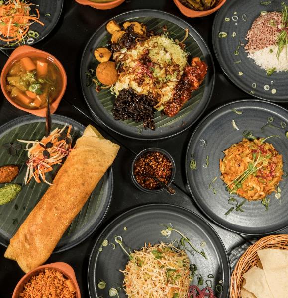 Traditional Sri Lankan dishes including curries, rice, dosa, and assorted condiments on black plates