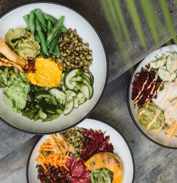 Vibrant plant-based buddha bowls with fresh vegetables and colourful toppings on a rustic table